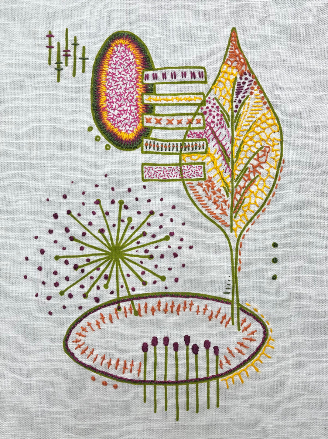 Modern hand embroidery on fabric featuring a colorful abstract leaf and geometric shapes, created using the Freestyle Embroidery Kit - Leaf Print with vibrant threads.