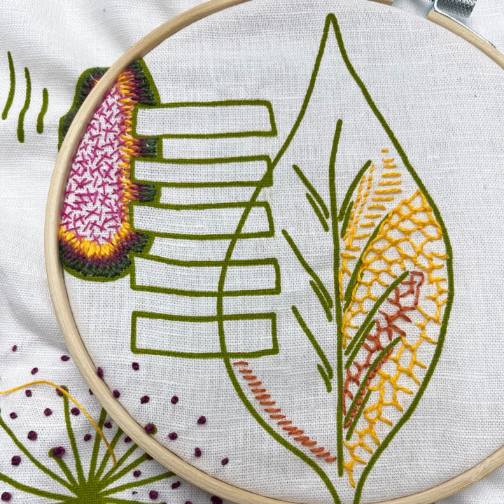 Close-up of a hand embroidery project featuring colorful detailed stitches on leaf designs using embroidery floss, part of the Freestyle Embroidery Kit - Leaf Print for modern needlework enthusiasts.