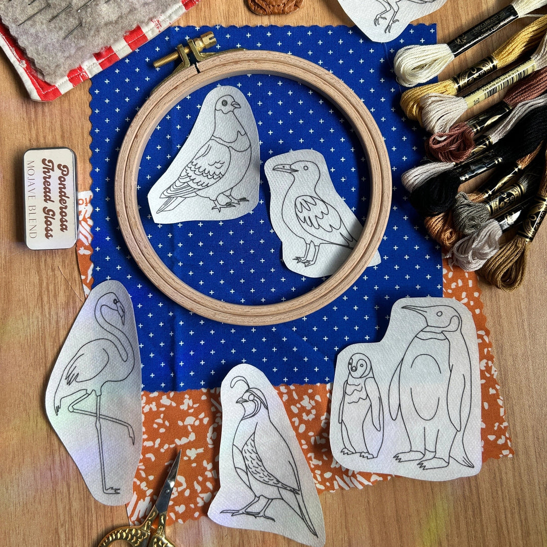 Odd Birds Stick & Stitch Embroidery Patterns displayed on fabric with embroidery floss, scissors, and a wooden hoop, highlighting modern needlework supplies for embroidery and cross stitch enthusiasts.